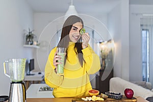 Young woman with glass of tasty healthy smoothie in kitchen . Smiling girl living healthy life. Happy woman holding kiwi on her