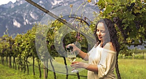 Young woman with a glass of white wine in the vineyards of Italy. Person pouring wine. Free space for text.