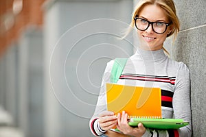 Young woman with glasses against wall of building