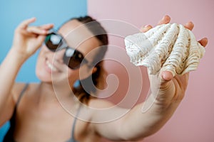 Young woman in glasses with a cockleshell. Summer concept