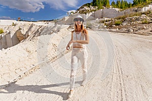 Young woman with glasses and hat running on the road in summer