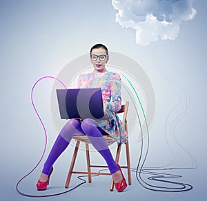 Young woman in glasses sitting on a chair with a laptop. Concept cloud computing.