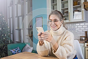 Young woman in glasses talking via mobile phone while resting in home