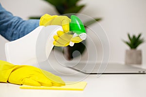 Young woman in gloves cleaning office table