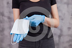 Young woman in gloves holding a mask in her hands