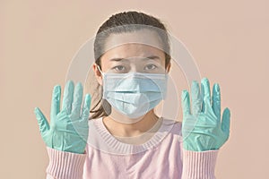 A young woman in gloves puts on a medical mask.