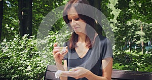 Young woman glut and can not eating burger anymore in the park sitting on bench