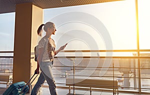 Young woman goes at airport at window with suitcase waiting for