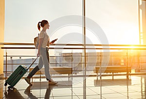 Young woman goes at airport at window with suitcase waiting for photo