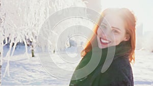 Young woman goes, turns to the camera and smiling, sunny winter day