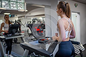 Young woman going on treadmill machine in fitness club.
