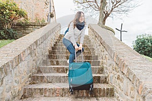 Young woman is going upstairs with her heavy luggage