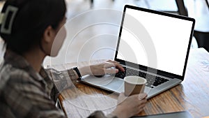 Young woman golding coffee cup and using laptop computer.