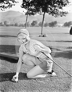 Young woman on a golf course placing a golf ball photo