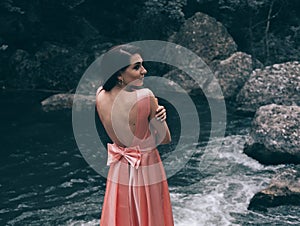 Young woman in gorgeous pink dress with waving flying fabric, fashion female posing in the park