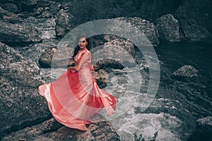 Young woman in gorgeous pink dress with waving flying fabric, fashion female posing in the park