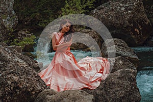 Young woman in gorgeous pink dress with waving flying fabric, fashion female posing in the park