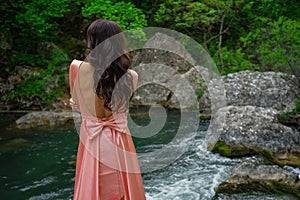 Young woman in gorgeous pink dress with waving flying fabric, fashion female posing in the park