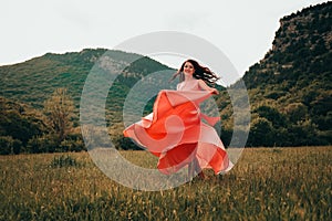 Young woman in gorgeous pink dress with waving flying fabric, fashion female posing in the park