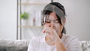 Young woman got a nose allergy sneezing sitting on the sofa at home. Flu, Influenza, Sick, Fever, Illness.