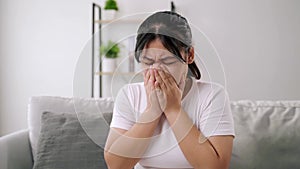 Young woman got a nose allergy sneezing sitting on the sofa at home. Flu, Influenza, Sick, Fever, Illness.