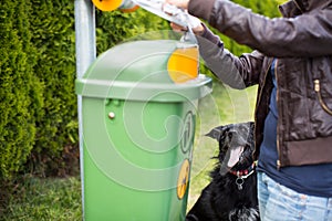 Young woman grabbing a plastic bag in a park to tidy up after her dog later
