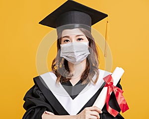 Young woman in graduation gowns with medical mask