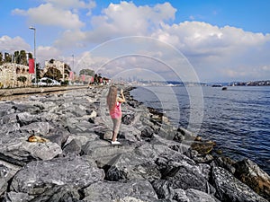 Young woman on a granite shore shoots the landscapes of Marmara sea and Istanbul on the horizon with a smartphone Turkey. Adult