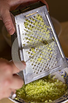 Young woman grating lemon peel for cake preparation