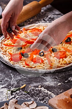 Young woman in a gray aprong prepares a vegetarian pizza