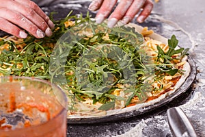 Young woman in a gray aprong prepares a vegetarian pizza