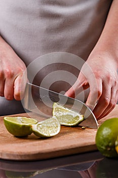 Young woman in a gray aprons cut lime