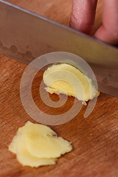 Young woman in a gray aprons cuts the root of ginger