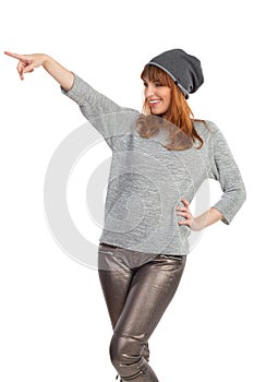 Young Woman In Gray Blouse, Shiny Pants And Winter Cap Is Pointing And Laughing