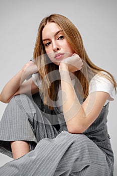 Young Woman in a Gray Suit Sitting on the Floor in Studio