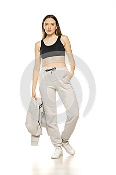 A young woman in a gray tracksuit and black top poses against a white background in the studio