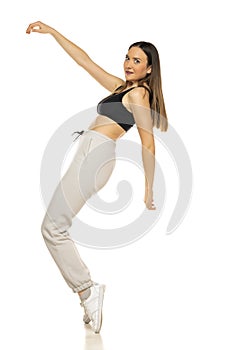 A young woman in a gray tracksuit and black top poses against a white background in the studio