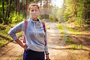 Young woman in green autumn forest. Portrait of cute girl in forest nature. Hikes in woodland. Hiking in wild nature