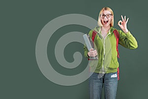 Young woman on green blackboard background - for text copy space. Female student thinking about coursework in university