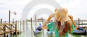 Young woman with green dress holding her hat when looking to Venice Lagoon. Panoramic banner view of traveler girl in