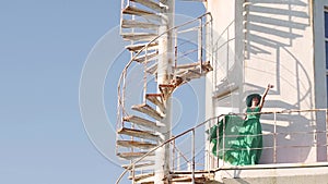 young woman in a green dress posing at the lighthouse against the backdrop of a beautiful landscape