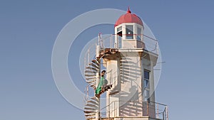 young woman in a green dress posing at the lighthouse against the backdrop of a beautiful landscape