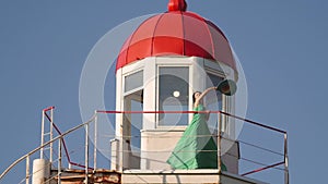 young woman in a green dress posing at the lighthouse against the backdrop of a beautiful landscape