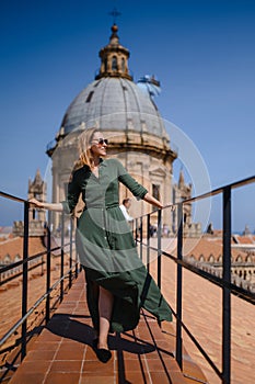 Young woman in a green dress on the roof of a catholic temple