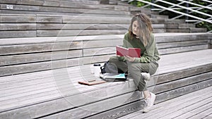 Young woman in green reading a book on the stairs