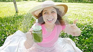 Young woman with green vegetable smoothies in the park