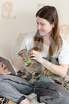 A young woman greets an online interlocutor and smiles. Woman holding a striped kitty
