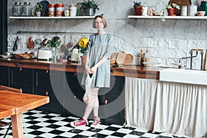 Young woman in grey dress with knitted rag bag string bag shopper in kitchen, zero waste, slow life