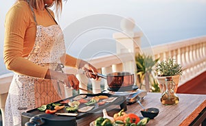 Young woman grill vegetables while preparing dinner in patio terrace outdoor - Food, healthy lifestyle and vegetarian concept -