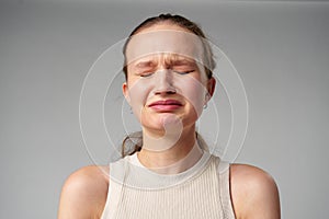 Young Woman Grimacing in Displeasure Against a Neutral Background